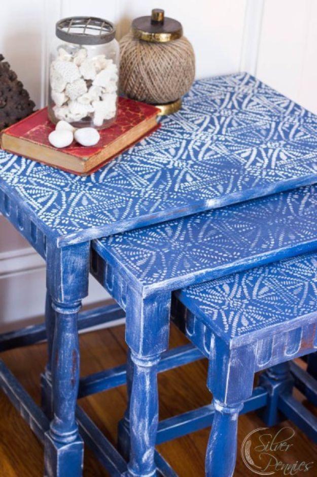Three bright blue nesting tables with white and gray stenciled batik patterned tops against a white wall