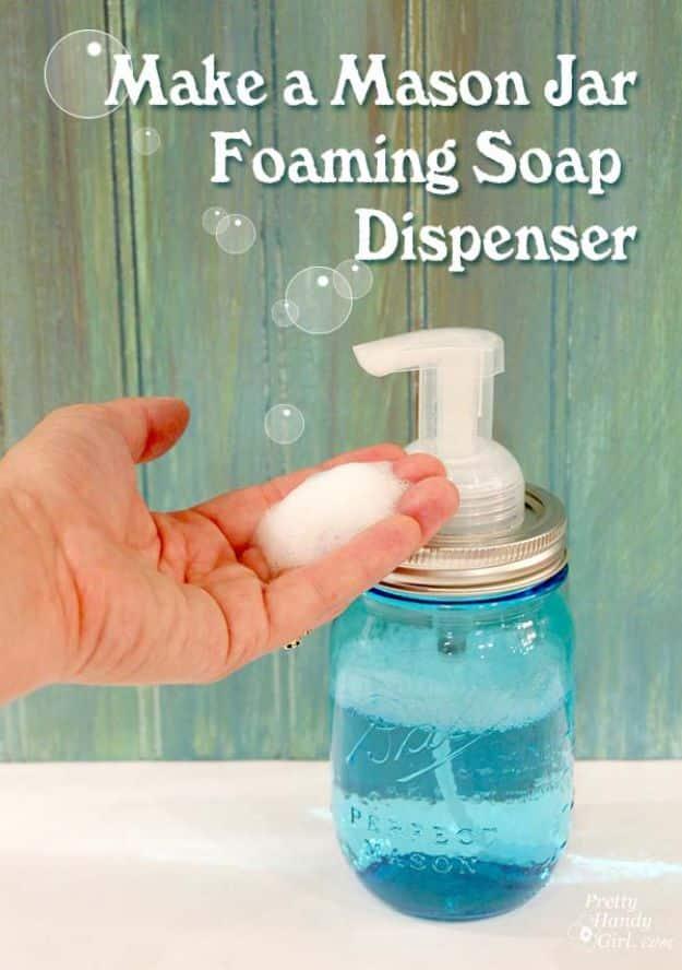 Blue Ball mason jar foaming soap dispenser pumping a dome of white foam into an open hand above a white counter