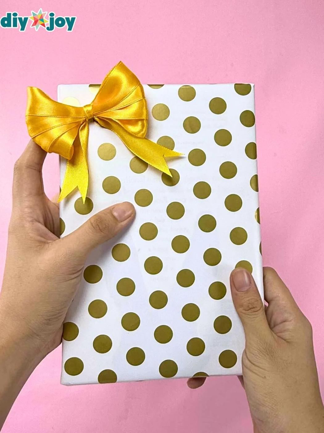 A gift wrapped on the diagonal with a short leftover piece of paper so the seams meet neatly across the top