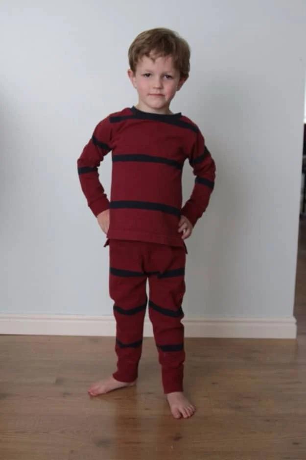 Sewing projects for boys pajamas in dark red and navy stripes sewn from a men's shirt, worn by a child indoors