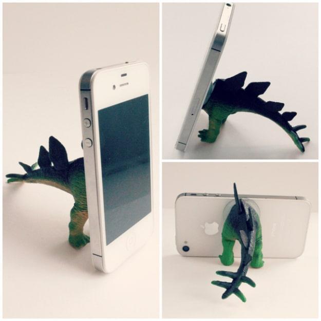 White phone propped upright by a green toy dinosaur's rear half fitted with a suction cup, shown in three views