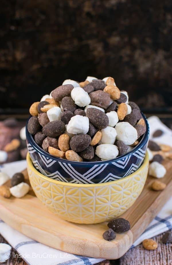Two stacked bowls heaped with hot cocoa trail mix of chocolate covered peanuts, yogurt covered pieces and peanuts