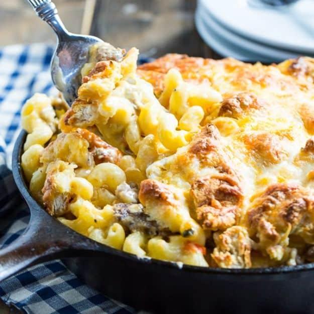 Breakfast mac and cheese in a cast iron skillet with sausage and a browned crumbled biscuit and egg topping