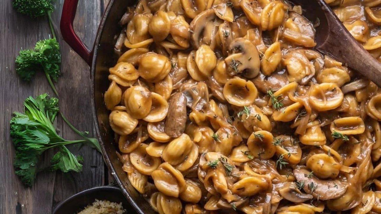 One pot French onion pasta, orecchiette in a glossy caramelized onion and mushroom sauce with fresh thyme in a skillet