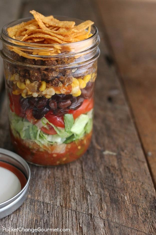 Taco salad in a jar layered with salsa and taco meat, black beans, corn, cheese, tortilla strips and lettuce