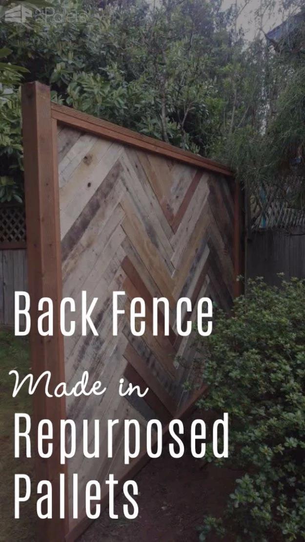 Pallet backyard fence, a framed panel of reclaimed pallet boards laid in a 45 degree herringbone pattern in a garden