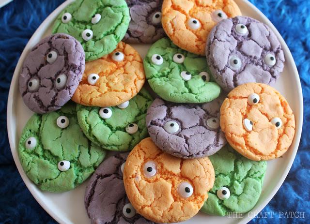 Orange, green and purple crackle monster cookies topped with different sizes of candy eyes on a serving plate