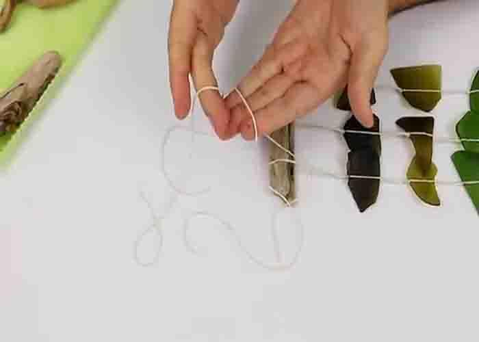 Tying the sea glass strands to the driftwood to complete the wind chime