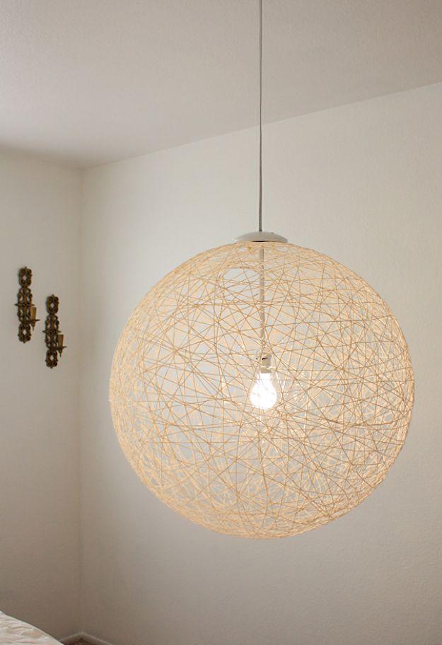 Large round cream yarn ball pendant light glowing on its cord against a plain white ceiling and wall