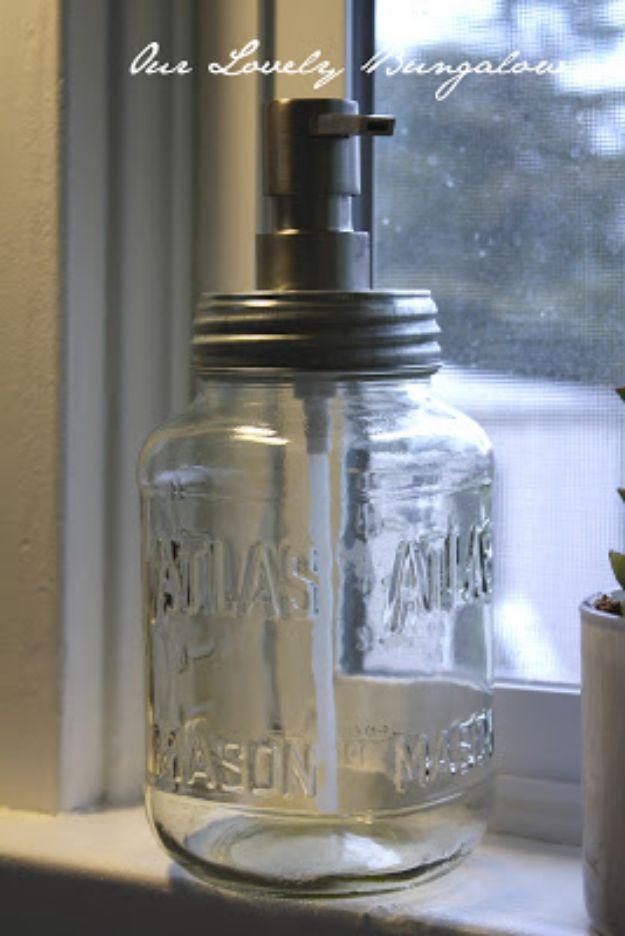 Clear Atlas and Mason jar soap dispenser with a dark metal pump and galvanized lid on a sunny window ledge