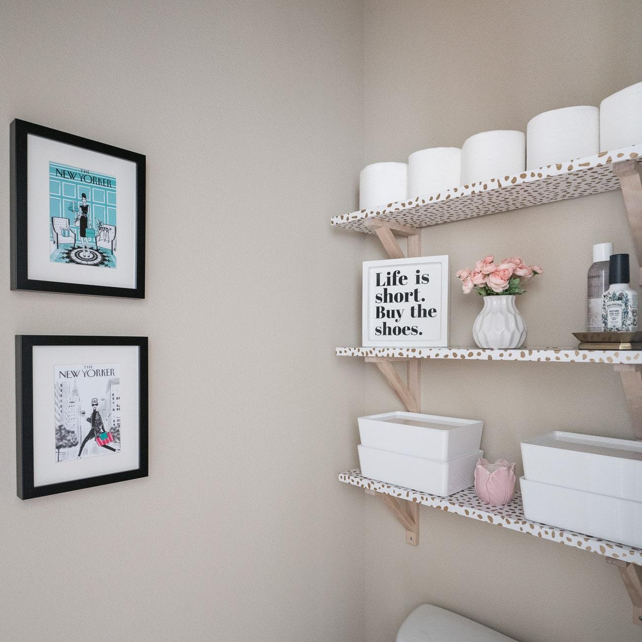 Over the toilet storage shelves in a small bathroom, a DIY bathroom decor idea using wallpaper wrapped wood