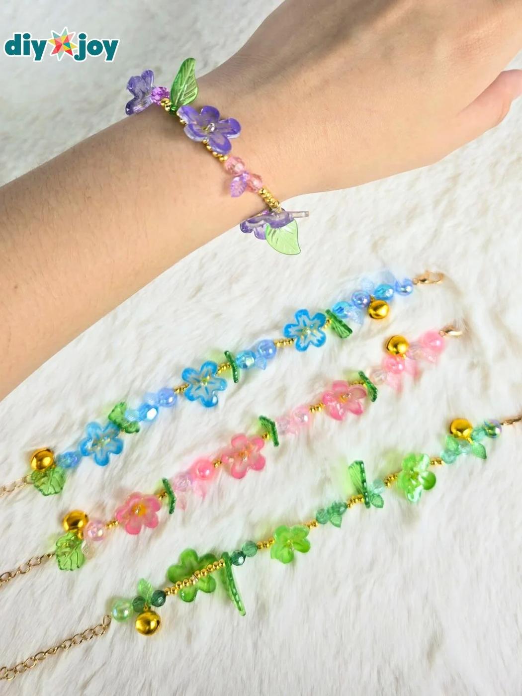 Stretch bracelet strung with glossy shrink plastic flower charms in pink, yellow and white on a pale surface