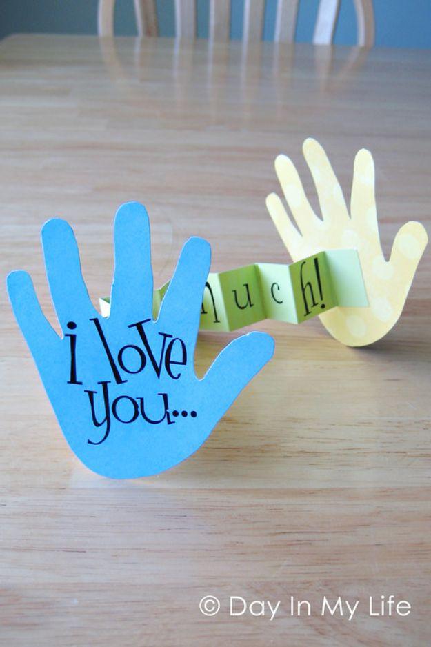 Two paper handprint cutouts in blue and yellow joined by a green accordion folded strip spelling out much