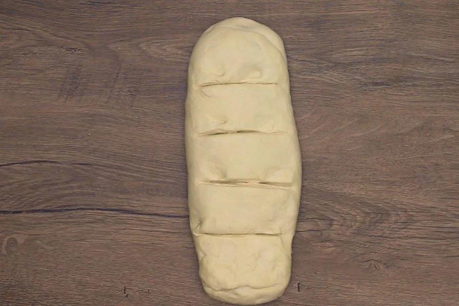 Shaped bread dough for copycat cinnamon bread on a wooden surface