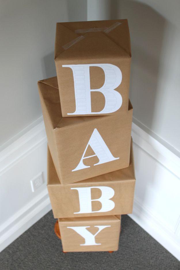 DIY baby shower decoration with diaper boxes wrapped in brown kraft paper and stacked to spell BABY in large white letters