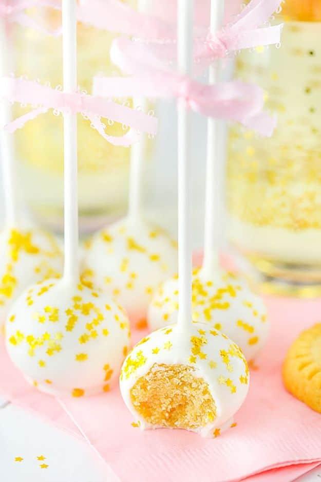 No bake champagne cookie pops, white dipped shortbread pops with gold sprinkles tied with pink ribbon