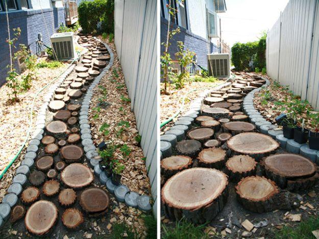 Garden pathway of round wood slices cut from logs, set into gravel and edged with stones beside a house