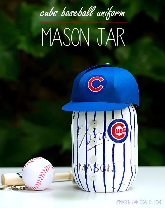 Mason jar painted as a Cubs baseball uniform with pinstripes and buttons, wearing a small blue cap, beside a baseball