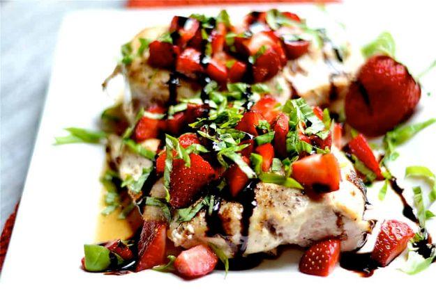 Strawberry basil chicken on a white plate topped with chopped berries, fresh basil and a balsamic drizzle