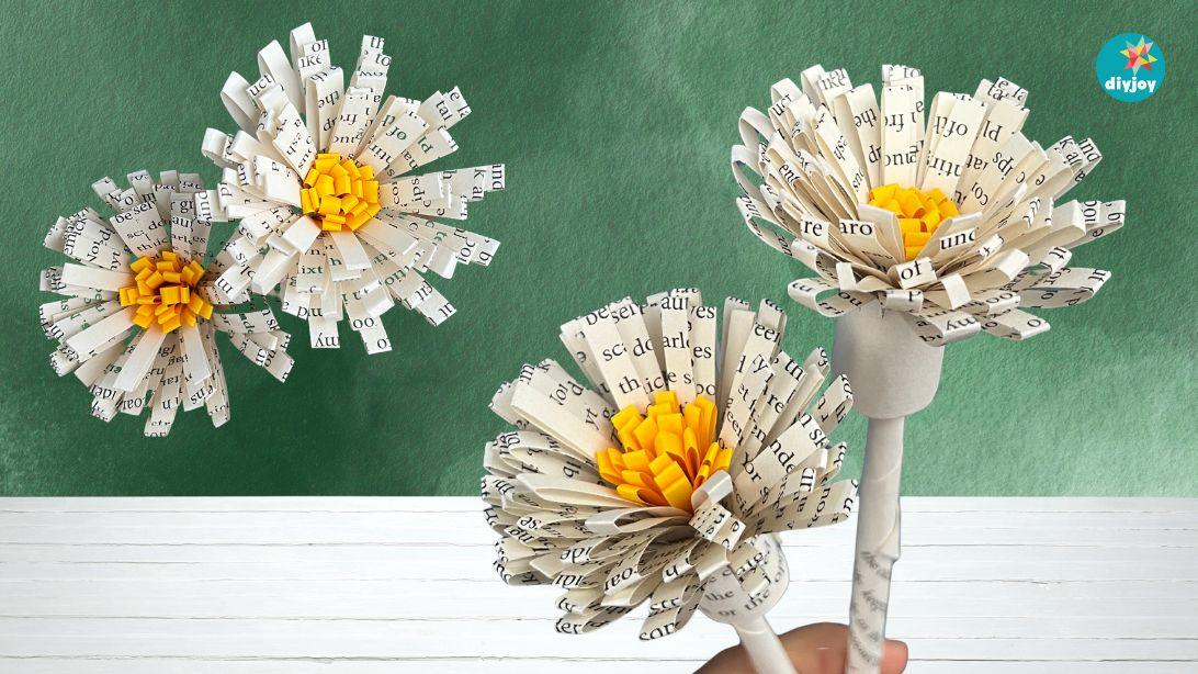 Book page paper flowers, three fringed white paper flowers with yellow centers on wire stems against dark green
