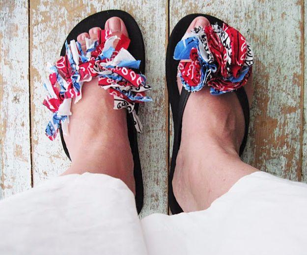 Bare feet in black flip flops covered with ruffled red, white and blue bandana strips on weathered wood