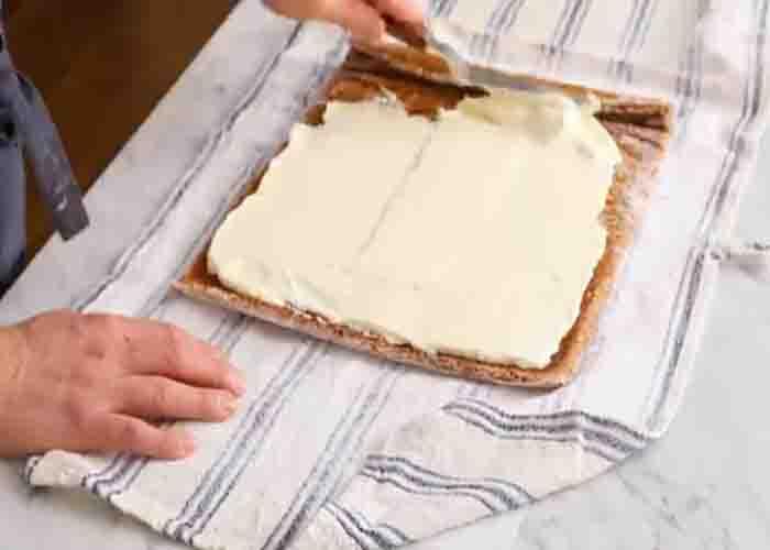 Spreading out the filling on the pumpkin cake roll