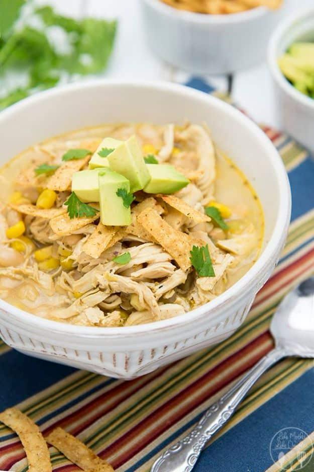 White chicken chili in a bowl topped with tortilla strips, diced avocado, cilantro and sour cream for a fast family dinner