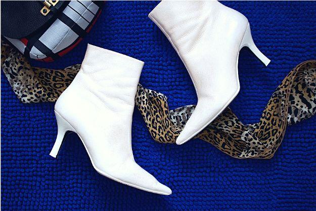 Update old boots with paint, white repainted leather ankle booties with pointed toes on a bright blue rug