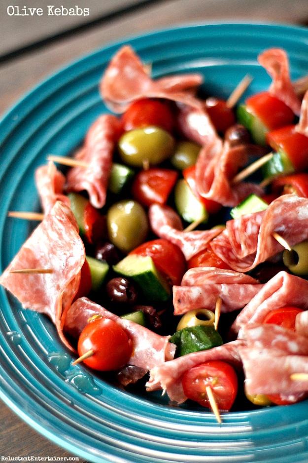 Olive kebabs party appetizer on cocktail toothpicks with folded salami, cucumber and cheese cubes on a platter