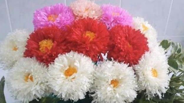 English daisy paper flowers, a dense mound of white, pink and red layered paper daisies with yellow centers
