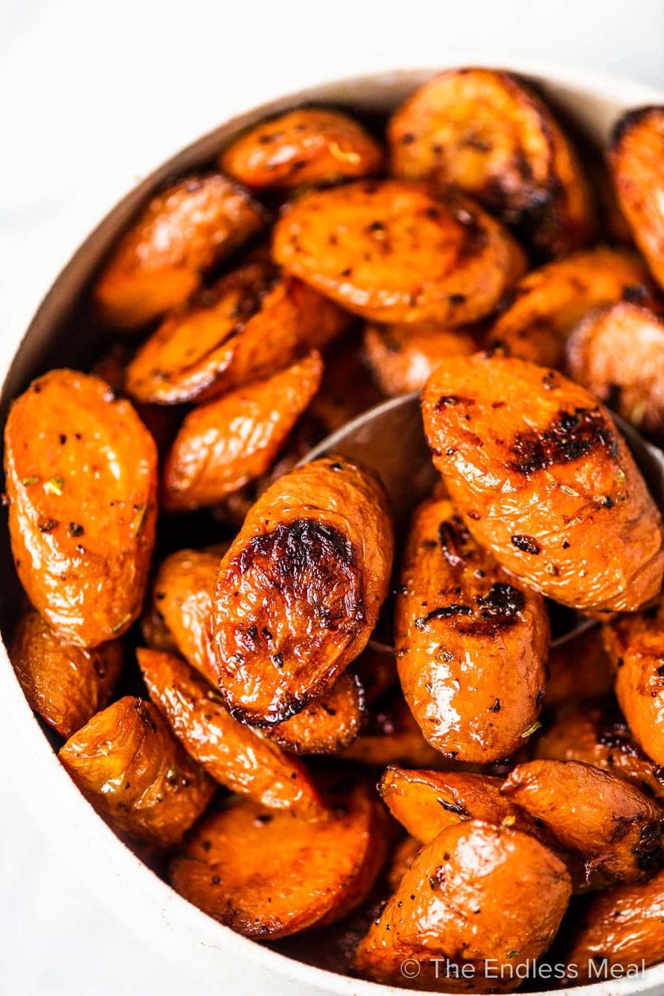 Garlic roasted carrots cut thick on the diagonal, caramelized dark at the edges on a large sheet pan