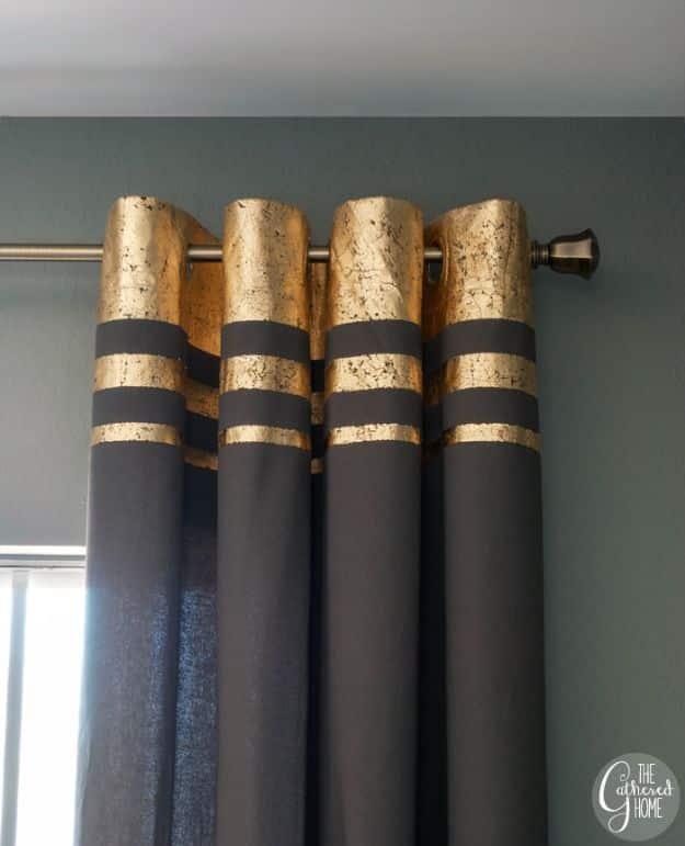 Dark gray curtain panels with gold leaf stripes across the top hanging on a rod against a green wall