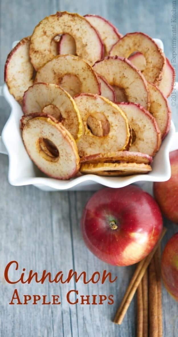Cinnamon apple chips spread across a baking sheet, sliced thin and dusted with cinnamon before drying