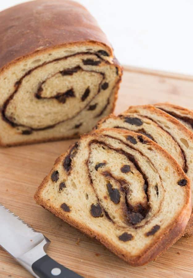 Cinnamon raisin bread sliced to show the dark cinnamon swirl and raisins spiraling through every single slice