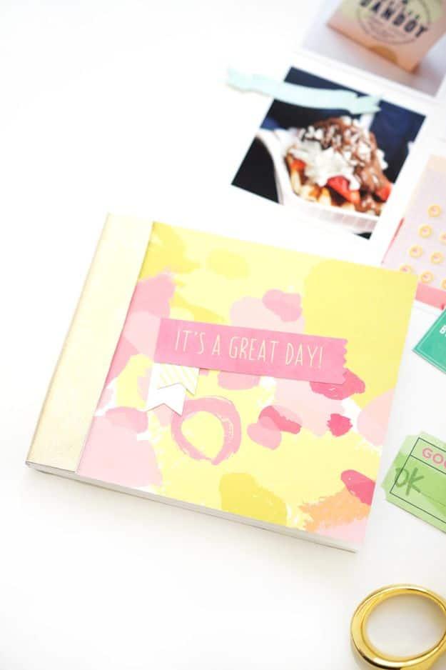 Easy photo journal with a pink and yellow watercolor cover, an It's A Great Day label and an instant photo above