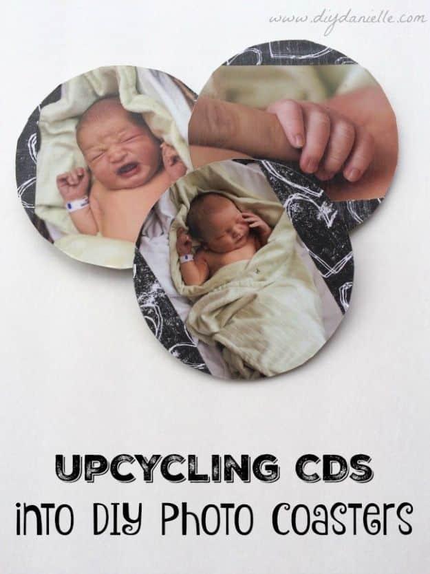 Three photo coasters made from CDs topped with baby photographs and black patterned paper, with a pin title