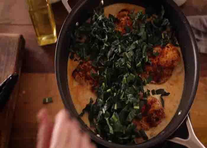 Adding the kale to the creamy chicken dijon