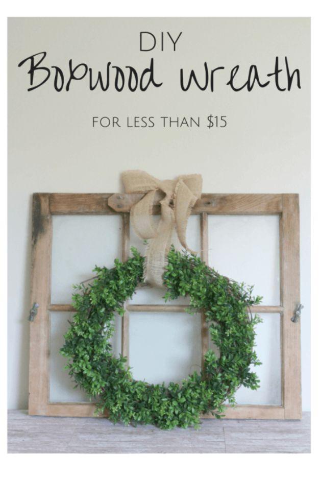 DIY boxwood wreath, a round green boxwood wreath with a wide burlap bow, hung on an old salvaged window frame