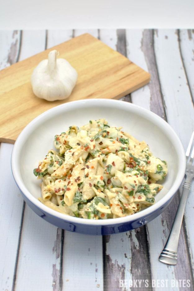 Creamy garlic spinach chicken pasta with wilted spinach and sliced chicken in a pale cream sauce ready to serve at home