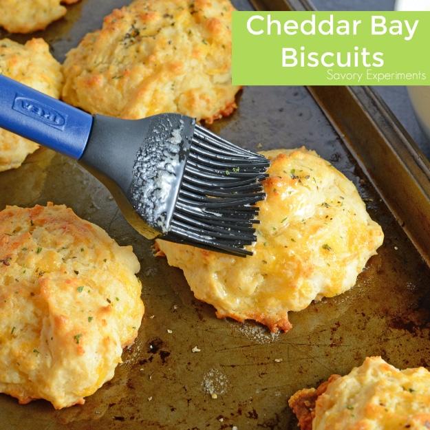 Copycat Red Lobster cheddar bay biscuits brushed with garlic parsley butter and cooling on parchment paper