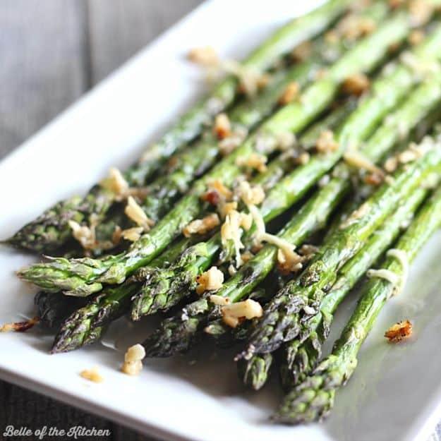 Garlic parmesan roasted asparagus on a white platter, roasted spears scattered with golden parmesan crumbs