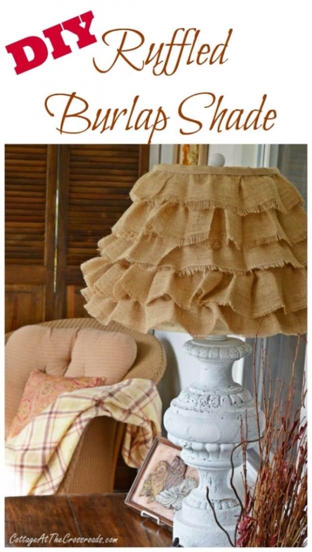 A lamp shade wrapped in rows of ruffled burlap sits on a dark ceramic lamp base beside a neutral linen armchair