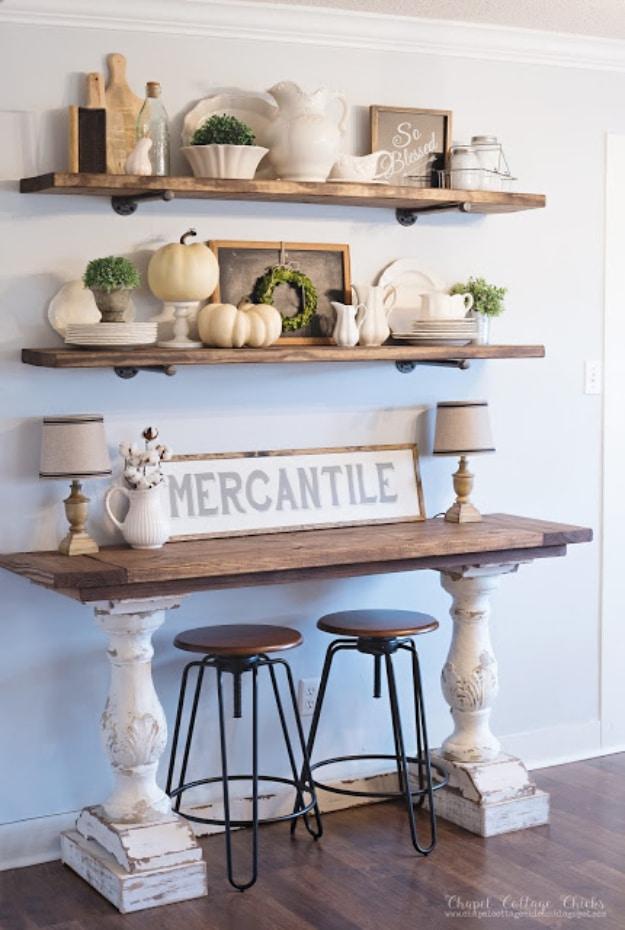 Two pipe shelves of white ironstone above a wood topped table on chippy white pedestals with a MERCANTILE sign and stools