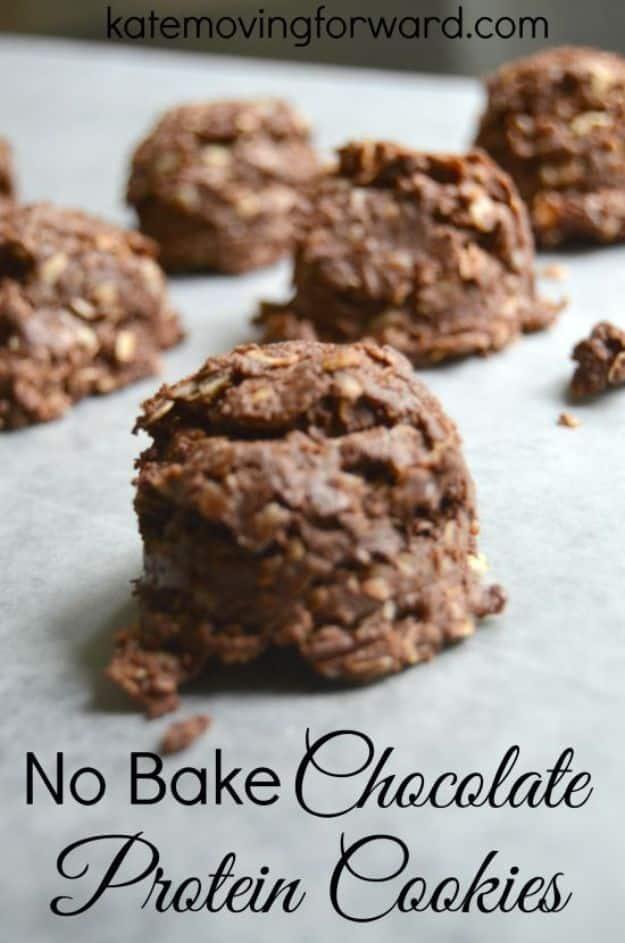 No bake chocolate protein cookies, dark chocolate oat mounds cooling in a row on white parchment paper