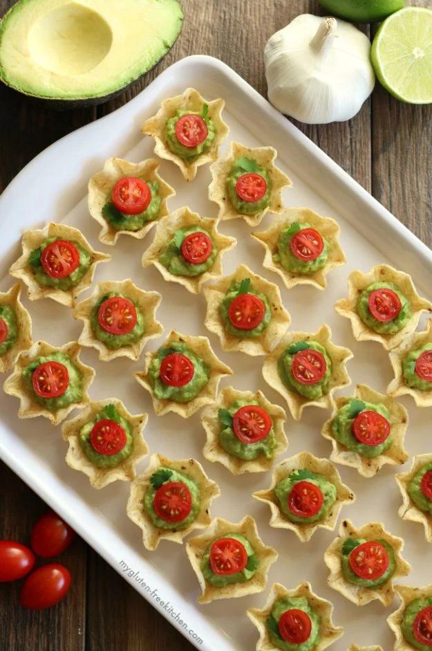 Gluten free chip and guacamole bites on a platter, scoop chips filled with guacamole, tomato and cilantro