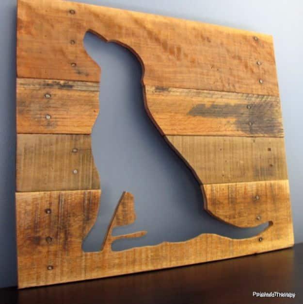Honey stained pallet board panel with a sitting dog cut out as negative space, the grey wall showing through it