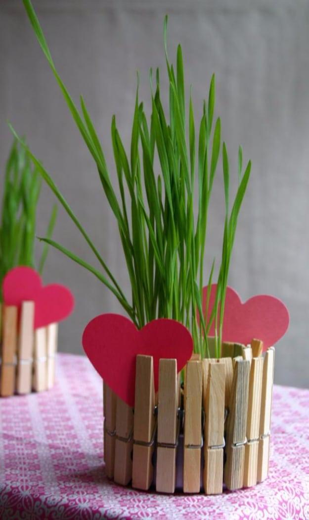 Wooden clothespins clipped around a tin can and stained warm brown, tied with ribbon and holding daisies