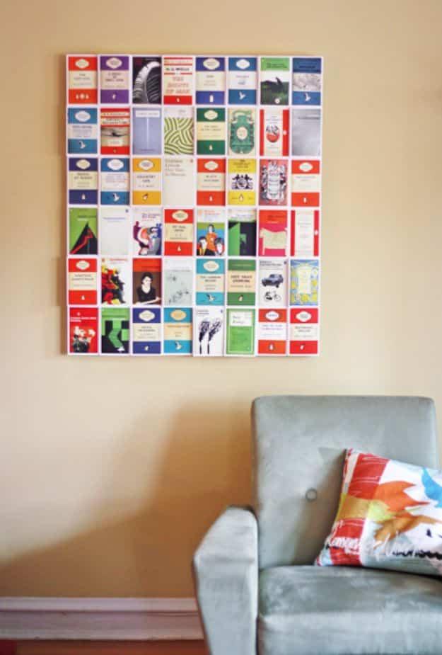 Grid of colorful vintage book cover postcards mounted on a large board above a gray armchair on a warm cream wall