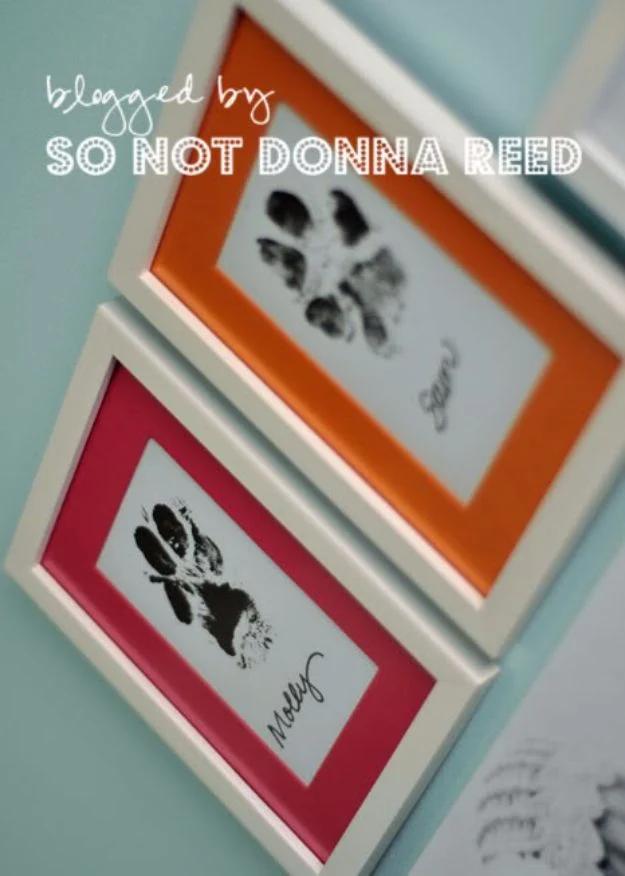 Photo captioned So Not Donna Reed showing two white frames with orange and pink mats holding black dog paw prints