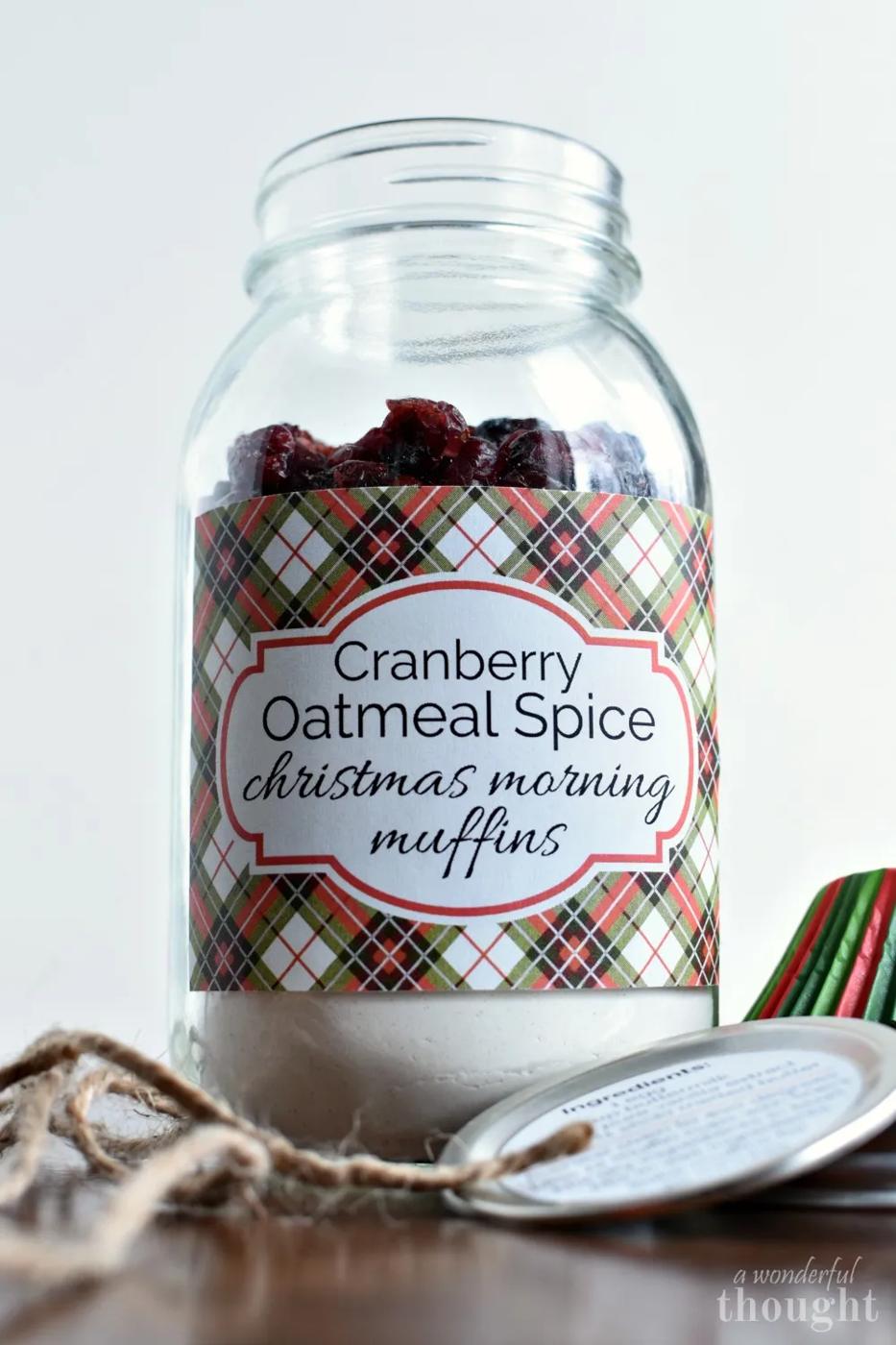 Mason jar layered with dry muffin mix ingredients beside baked muffins, tied with ribbon and a holiday gift tag